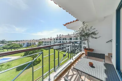 a balcony with a table and a view of a building at Apartamento Vila Sol com terraço e jacuzzi privad in Quarteira