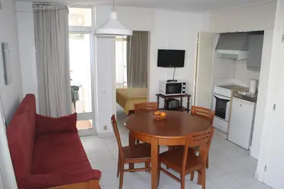 a kitchen and a living room with a table and a couch at Edificio Albufeira Apartamentos A. Local - Albuturismo Lda in Albufeira