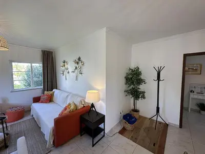 a living room with a white couch and a chandelier at Citymar by FHR T2 com piscina in Vilamoura