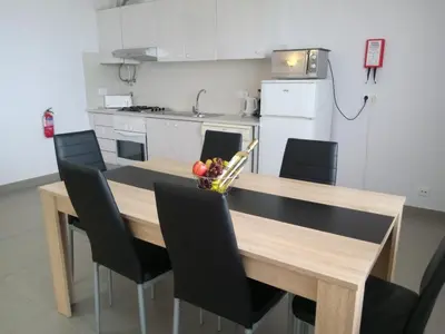 a kitchen with a wooden table with black chairs at Mamamia AC&Vista Magnifica in Quarteira
