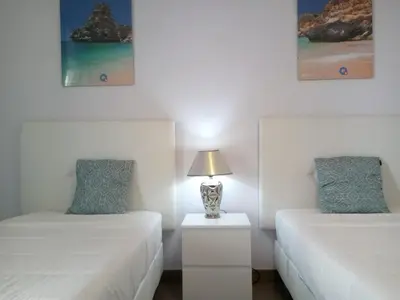 two beds in a room with a lamp on a night stand at Mamamia AC&Vista Magnifica in Quarteira
