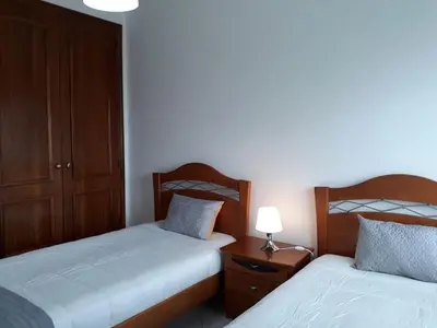 a bedroom with two beds and a table with a lamp at SATÉLITE AC&Garagem in Quarteira