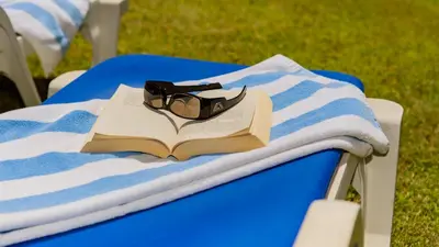 a pair of glasses sitting on a book on a chair at 3 Bed Holiday Home Lakeside Village Quinta Do Lago in Faro