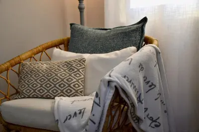 a wicker chair with pillows and a blanket on it at Aquamarine - Gemstone Getaway in Vale do Lobo