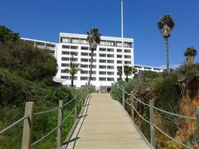 a walkway leading to a white building with palm trees at Apartamento Praia da Falésia in Albufeira