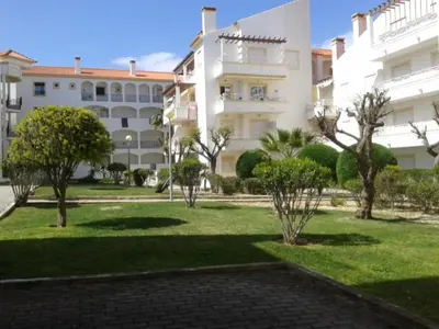 a large white building with trees in a park at Apartamento Praia da Falésia in Albufeira