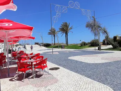 a group of red chairs and a table with a red umbrella at Avenida Mar- Vista Mar, Wifi, 150mt Praia in Quarteira