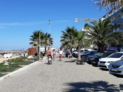 a group of people walking down a sidewalk near the beach at T2 Mira Praia 4- Familiar, 80mt Praia, Wifi in Quarteira