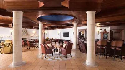 a lobby with chairs and a table and a dining room at Pine Cliffs Gardens in Albufeira