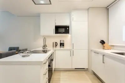 a kitchen with white cabinets and a microwave at Pine Cliffs Gardens in Albufeira