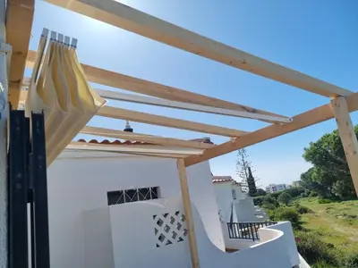 a pergola on the side of a white house at Quinta Shiamar in Quarteira