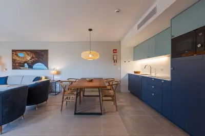 a kitchen and dining room with blue cabinets and a table at Hapimag Resort Albufeira in Albufeira