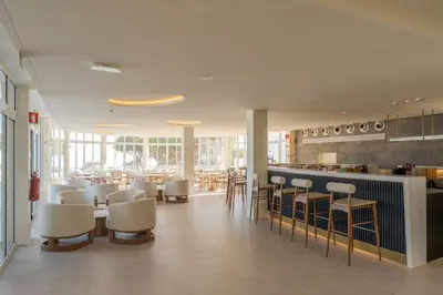 a restaurant with white chairs and tables and a bar at Hapimag Resort Albufeira in Albufeira
