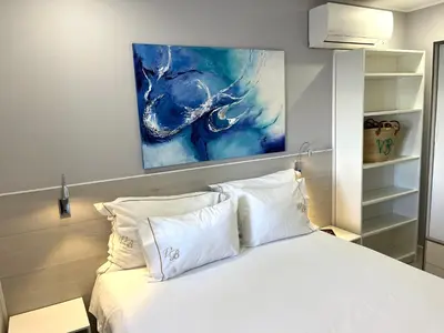 a bedroom with a white bed with a painting on the wall at Apartamento Villa Bellevue vista mar in Albufeira