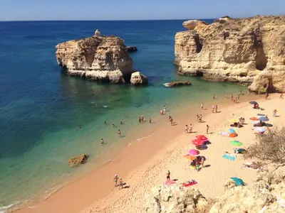 a group of people on a beach with umbrellas at Apartamento Villa Bellevue vista mar in Albufeira