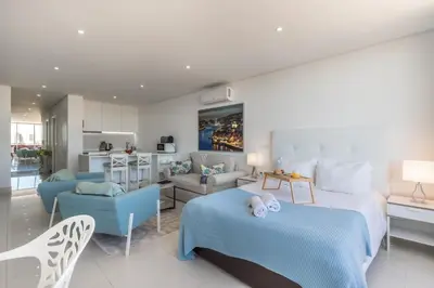 a bedroom with a bed and a living room at Estúdios Marina in Vilamoura