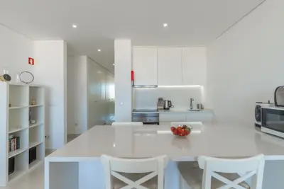 a white kitchen with a table and two chairs at Estúdios Marina in Vilamoura