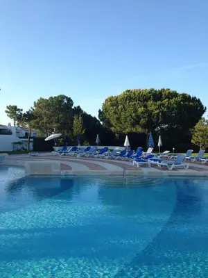 a group of lounge chairs and a swimming pool at Victory Village Club in Quinta do Lago