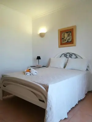 a bedroom with a large white bed with a table at Quinta Das Palmeiras in Quarteira