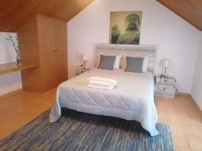 a bedroom with a white bed with a painting on the wall at Quinta Das Palmeiras in Quarteira