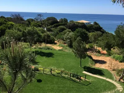 a park with green grass and trees and the ocean at Apartamento Praia da Oura in Albufeira