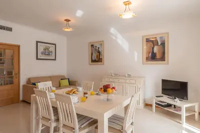 a living room with a table with chairs and a television at Apartamento Praia da Oura in Albufeira