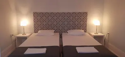 two beds in a small room with two lamps at Hostel A Casa da Árvore in Faro