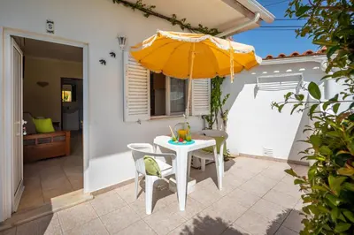 a patio with a white table and an umbrella at Apartamentos Flor da Laranja, Albufeira by AlgarveBlossom in Albufeira