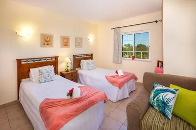 a bedroom with two beds and a couch and a window at Apartamentos Monte dos Avós, Albufeira by AlgarveBlossom in Albufeira