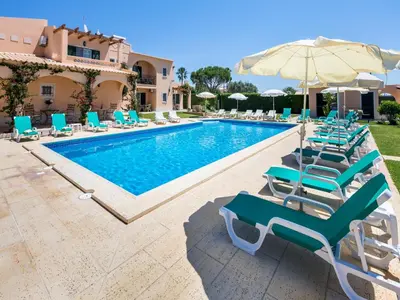 a swimming pool with lounge chairs and an umbrella at Apartamentos Monte dos Avós, Albufeira by AlgarveBlossom in Albufeira
