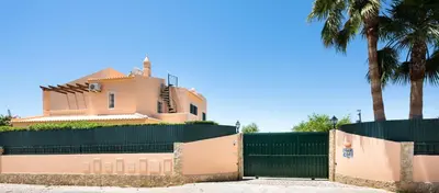 a house behind a fence with palm trees at Apartamentos Monte dos Avós, Albufeira by AlgarveBlossom in Albufeira