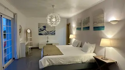 a bedroom with a large white bed and a chandelier at Fonte Santa by Check-in Portugal in Quarteira