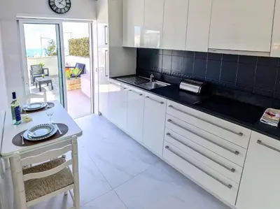a kitchen with white cabinets and a table with a sink at Casa beira mar Algarve in Albufeira