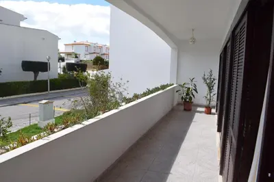 a balcony with a white wall and plants at Apartamento T2 com Piscina e Wifi a 350 metros da Praia in Roja- Pé