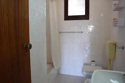 a bathroom with a toilet and a window at Apartamento T2 com Piscina e Wifi a 350 metros da Praia in Roja- Pé