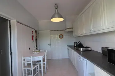 a kitchen with white cabinets and a table in it at APARTAMENTO MICÁ in Albufeira