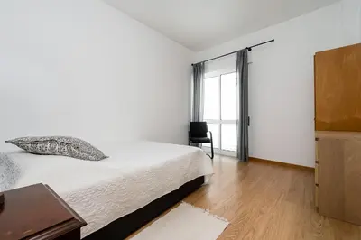 a white bedroom with a bed and a window at Casa Gago in Faro