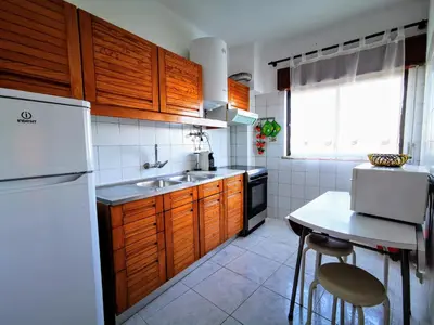 a kitchen with wooden cabinets and a sink and a table at Vista Mar 2 in Albufeira