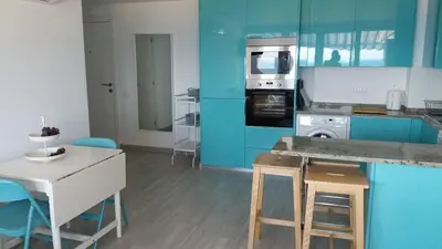 a kitchen with blue cabinets and a table and chairs at Edifício Albufeira 406 in Albufeira