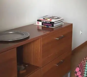 a wooden dresser with a stack of books on it at Your place in Faro in Faro