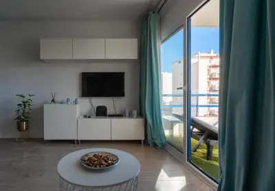a living room with a table and a large window at Apartamento Deluxe AM in Quarteira
