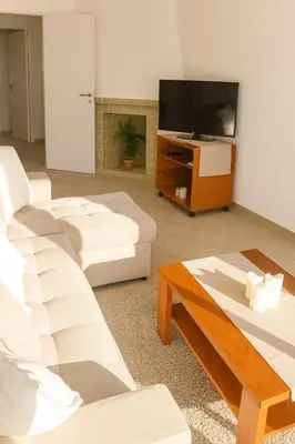 a living room with white furniture and a flat screen tv at sol nascente in Vilamoura