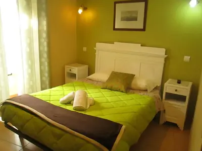 a green bedroom with a bed with green sheets at Guest House Capitao Mor in Faro