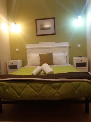 a bedroom with a green bed with two pillows at Guest House Capitao Mor in Faro