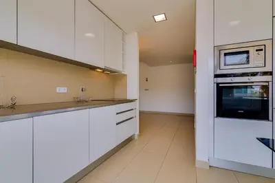 a kitchen with white cabinets and a microwave at Cavalo Preto Beach Resort in Quarteira