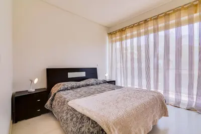 a bedroom with a bed and a large window at Cavalo Preto Beach Resort in Quarteira