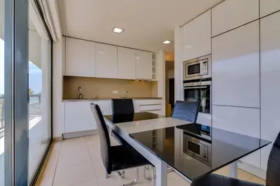 a kitchen with white cabinets and a table and chairs at Cavalo Preto Beach Resort in Quarteira