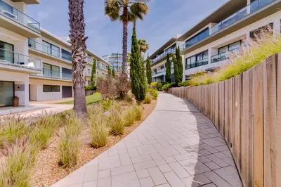 a sidewalk in front of a building with palm trees at Cavalo Preto Beach Resort in Quarteira
