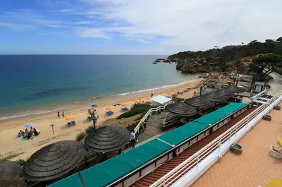 a view of a beach with umbrellas and a train at venha nadar a oura in Albufeira
