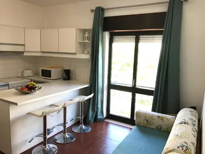 a kitchen with a window and a counter with stools at BREEZY NEST by ITHOUSE in Albufeira
